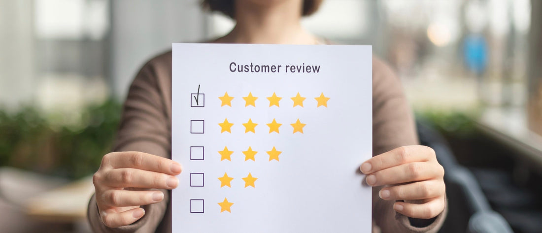 Klant houdt reviewkaart vast met vijf sterren beoordeling voor Vitamines.com reviews en klanttevredenheid