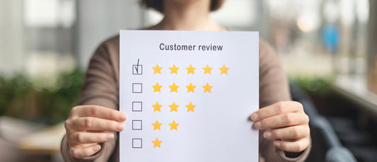 Klant houdt reviewkaart vast met vijf sterren beoordeling voor Vitamines.com reviews en klanttevredenheid