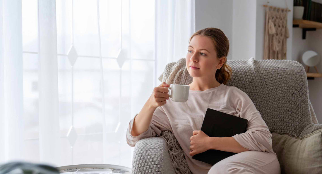 Vrouw ontspant met thee en boek op de bank
