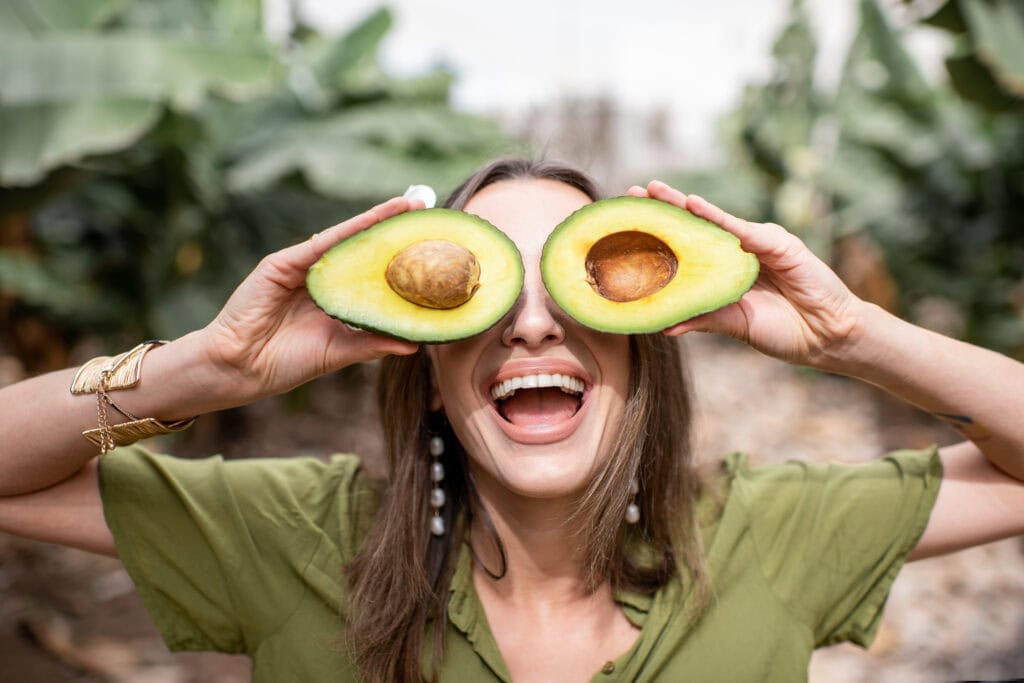 Vrouw met avocado dat goede vetten en gezonde vetten bevat